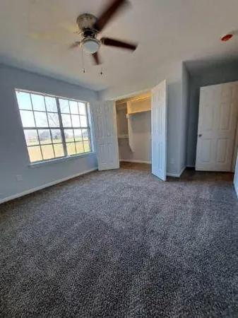 an empty room with windows and fan