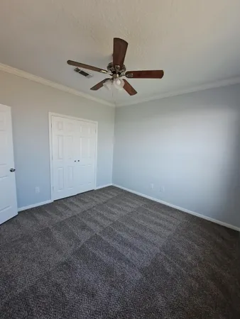 an empty room with a ceiling fan and window