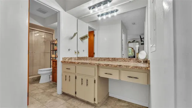 a bathroom with a granite countertop sink a toilet and a mirror