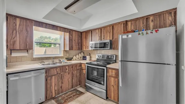 a kitchen with a refrigerator a sink stainless steel appliances cabinets and a window