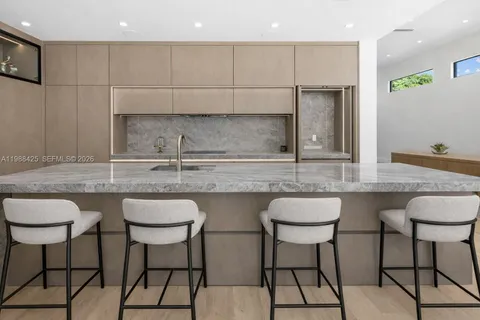 a kitchen with stainless steel appliances granite countertop a table chairs stove and sink