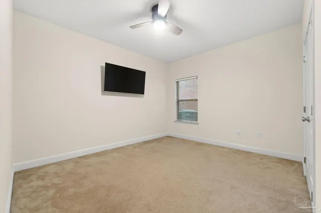 en empty room with ceiling fan and window