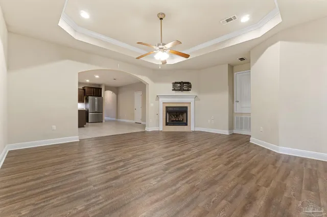 a view of an empty room with wooden floor fireplace and a window