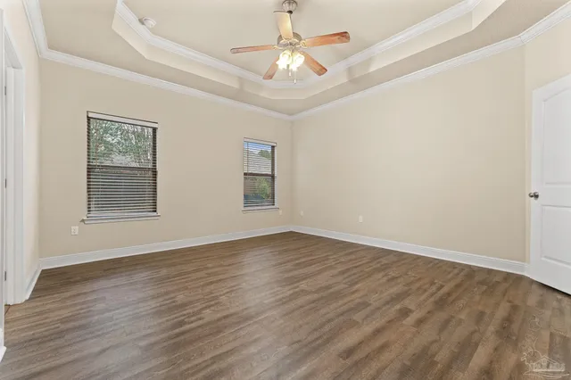 an empty room with wooden floor chandelier fan and windows