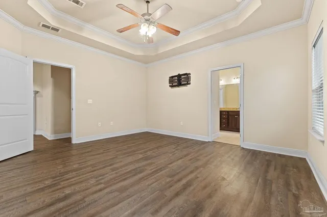 an empty room with wooden floor chandelier fan and windows