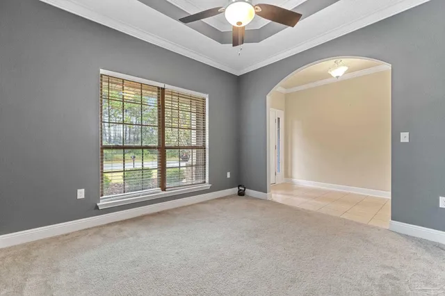 an empty room with chandelier fan and windows