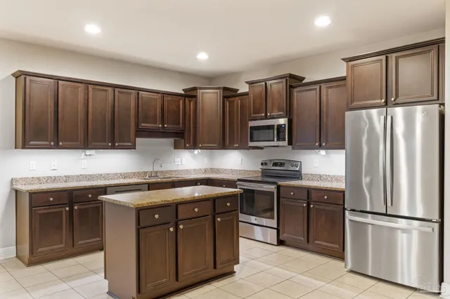 a kitchen with stainless steel appliances granite countertop a stove top oven a refrigerator and a sink
