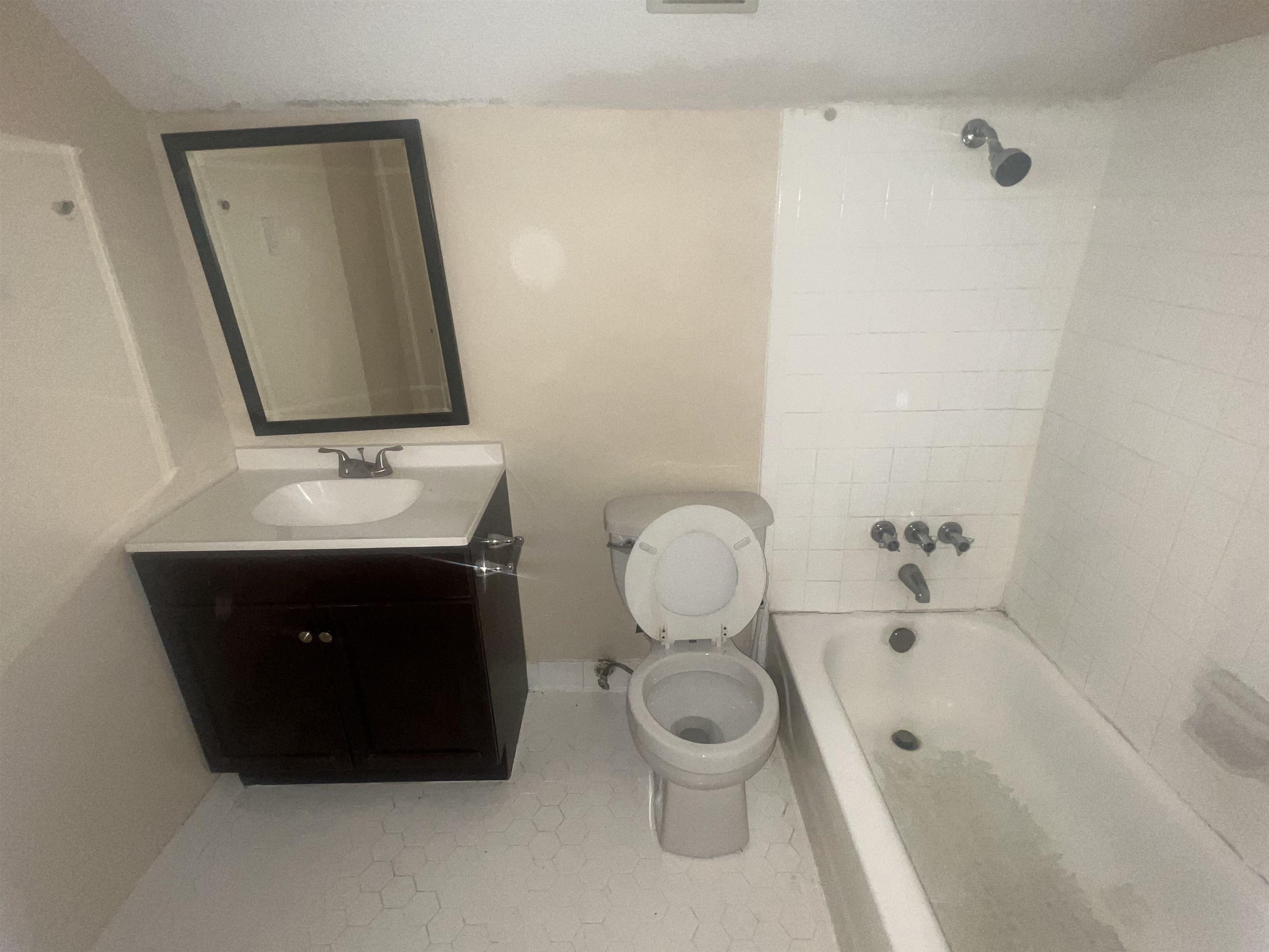 4295 Hudgins Road Memphis, TN 38116 - Photo 10 of 16 Bathroom featuring a dark wood-finish vanity with an integrated sink, framed mirror, white hexagonal floor tiles, and a tub with white subway tile surround