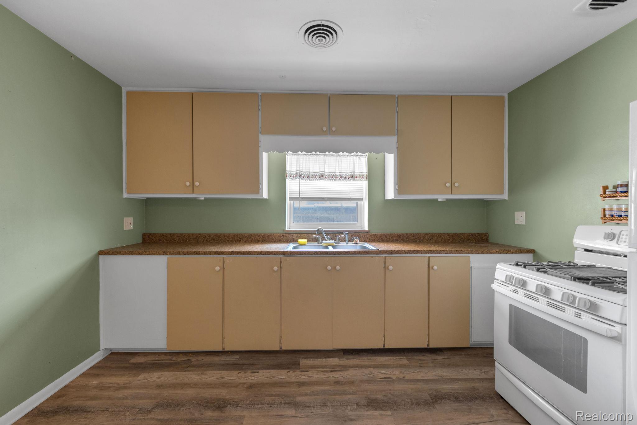 5223 Allen Road Allen Park, MI 48101 - Photo 7 of 12 Kitchen featuring wood-finish flooring, light green walls, a window above the sink, and a white gas range