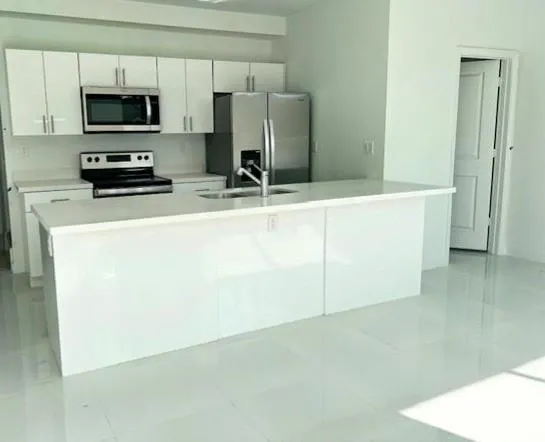 a kitchen with stainless steel appliances a stove top oven a sink a refrigerator and white cabinets