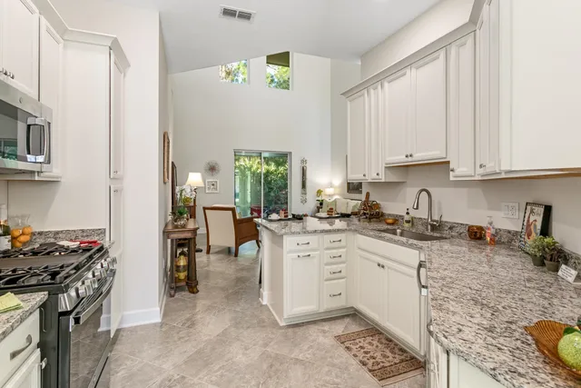 a kitchen with granite countertop white cabinets and white appliances