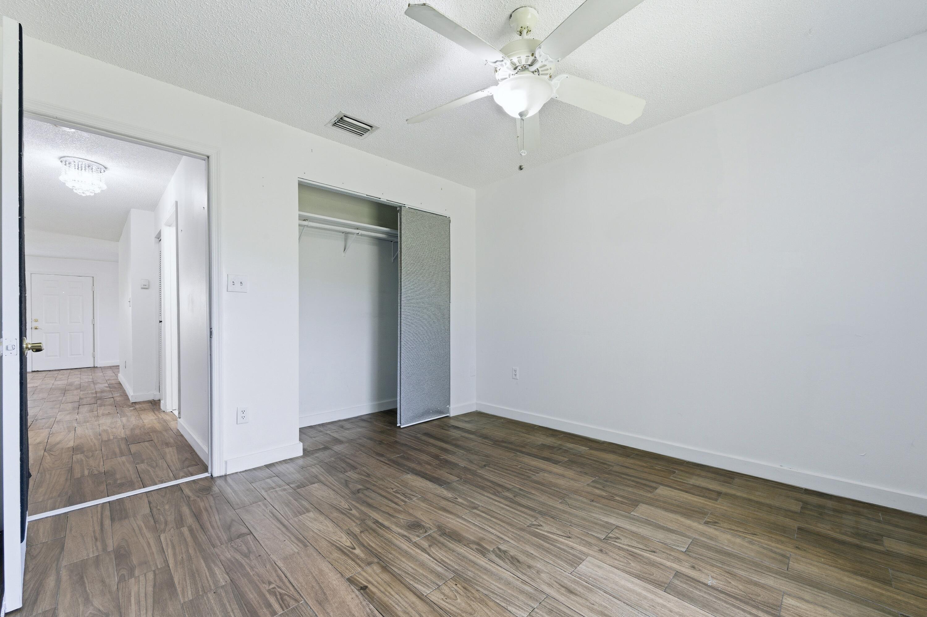 6088 Heather Street Jupiter, FL 33458 - Photo 13 of 18 an empty room with wooden floor and fan
