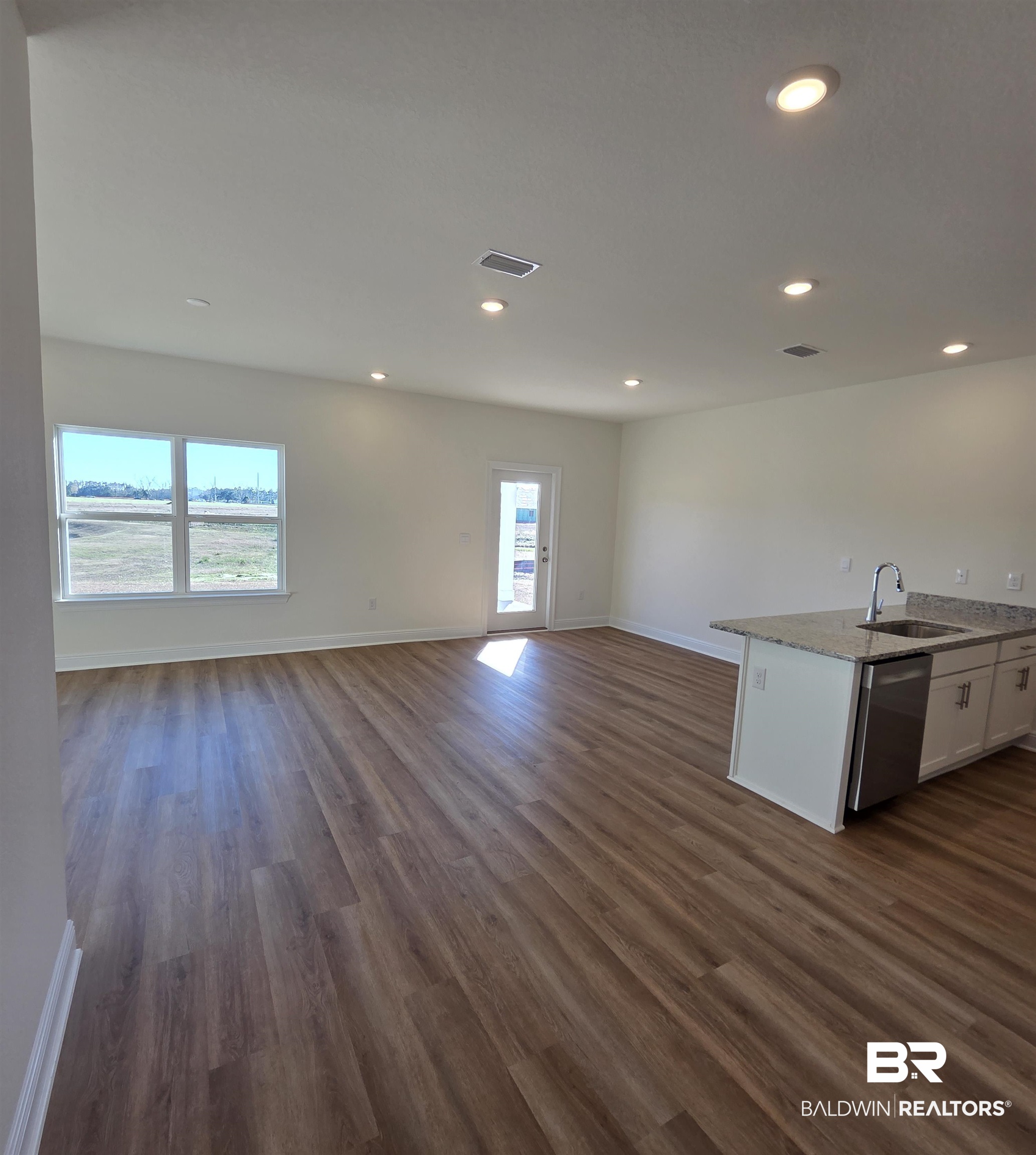 28084 Hallow Trail Elberta, AL 36530 - Photo 17 of 21 Kitchen with open floor plan, light stone countertops, dark wood finished floors, white cabinets, and dishwasher