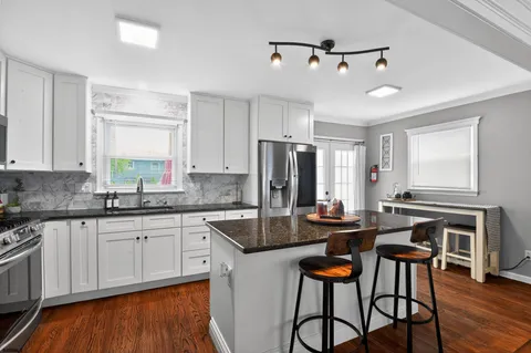 a kitchen with stainless steel appliances granite countertop a stove a sink dishwasher a dining table and chairs with wooden floor