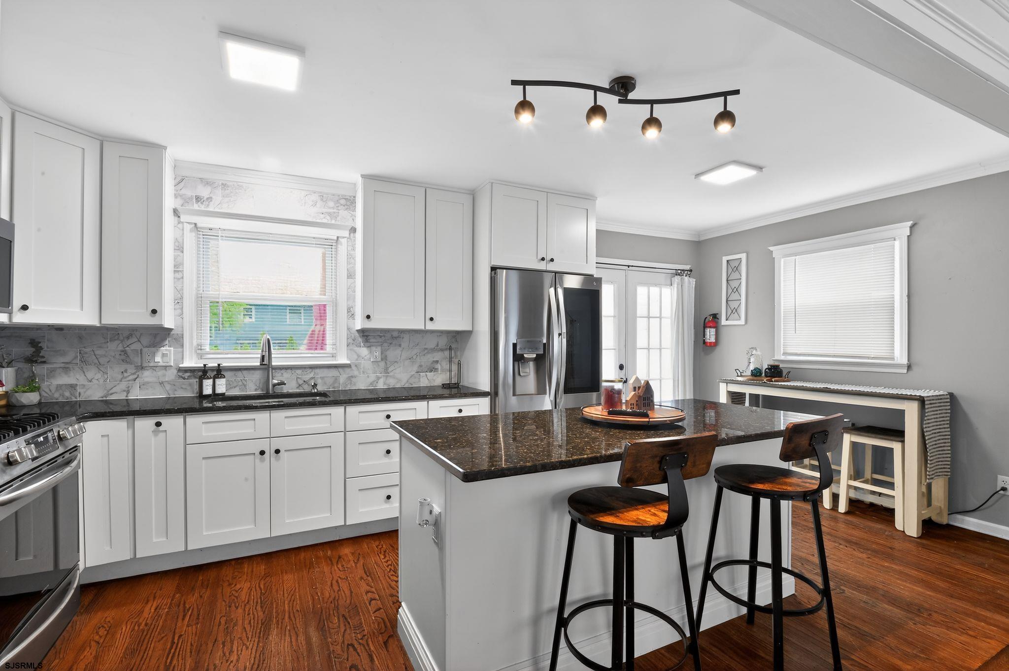 5 Merion Drive Somers Point, NJ 08244 - Photo 12 of 29 a kitchen with stainless steel appliances granite countertop a stove a sink dishwasher a dining table and chairs with wooden floor
