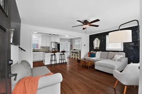 a living room with furniture kitchen view and a wooden floor