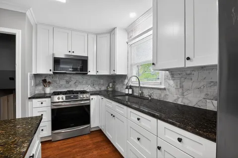 a kitchen with granite countertop white cabinets and appliances