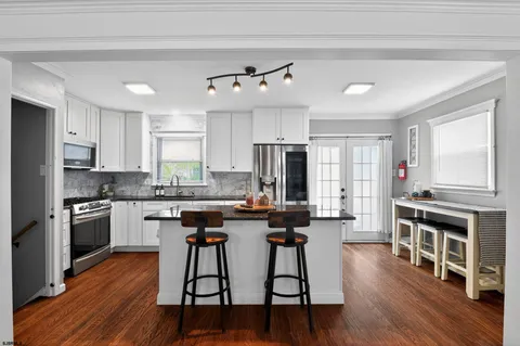 a kitchen with stainless steel appliances granite countertop a stove top oven a refrigerator a dining table and chairs with wooden floor