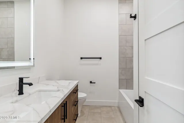 a bathroom with a granite countertop sink and a toilet