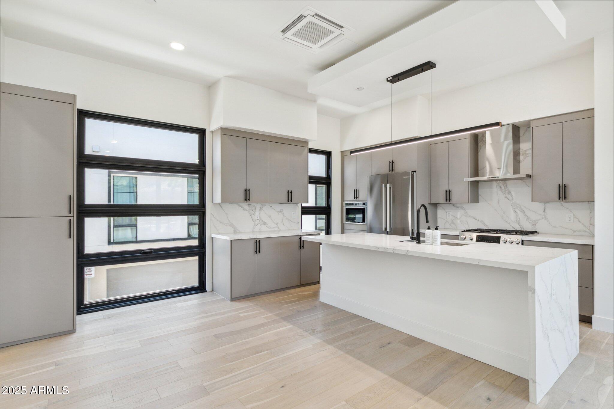 1501 North Miller Road, Unit 1016 Scottsdale, AZ 85257 - Photo 6 of 23 a large white kitchen with stainless steel appliances a stove top oven a sink and a refrigerator