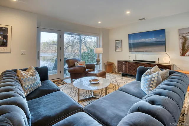a living room with furniture a flat screen tv and a large window