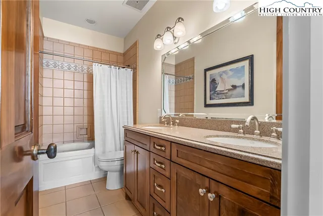 a bathroom with a double vanity sink toilet mirror and shower