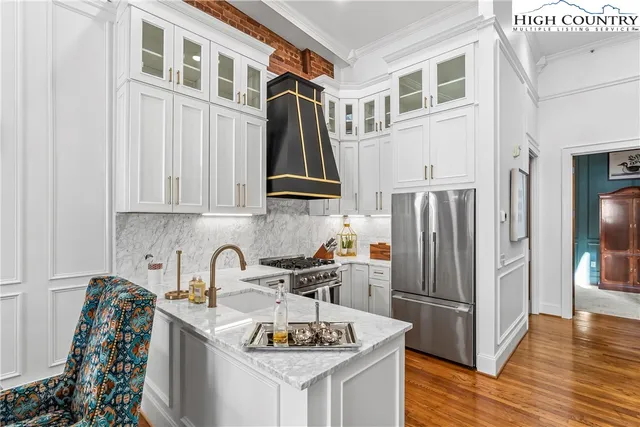 a kitchen with stainless steel appliances granite countertop a refrigerator a stove a sink and a dining table with wooden floor