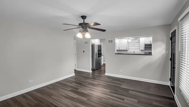 a view of a big room with wooden floor and a chandelier fan