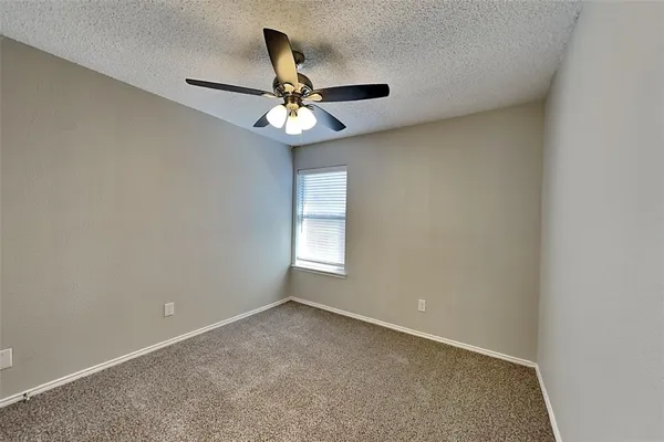 an empty room with a window and a fan
