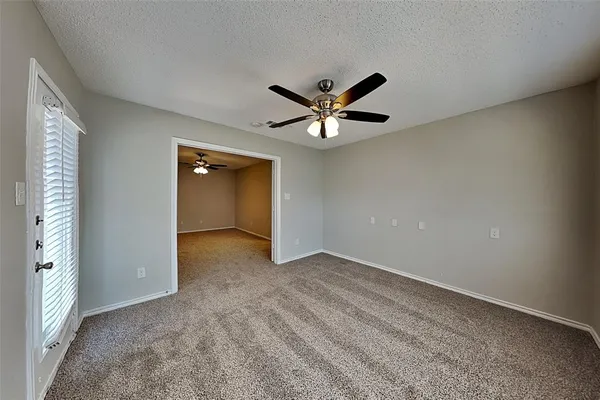an empty room with a ceiling fan and window
