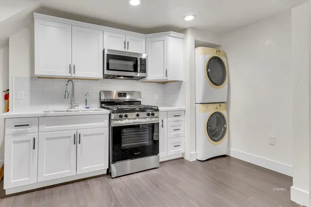 a view of a kitchen with stainless steel appliances wooden floor and chair
