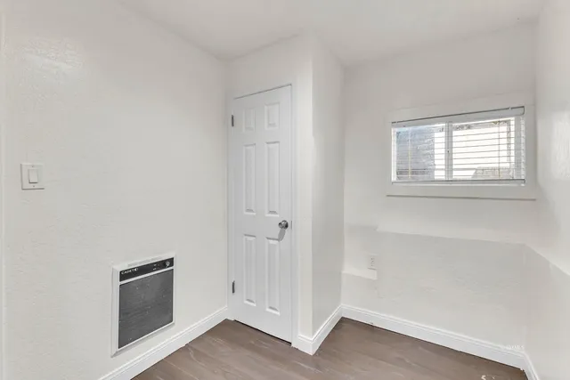 a view of empty room with wooden floor fan and window