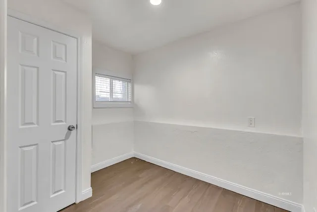 a view of an empty room with a window and wooden floor