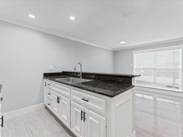 a kitchen with granite countertop white cabinets and a sink