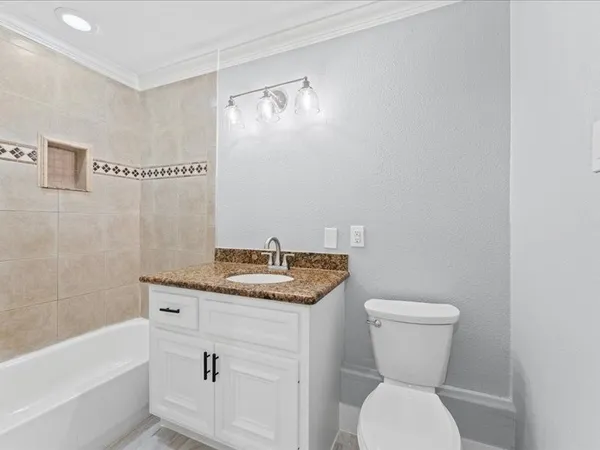 a bathroom with a granite countertop sink a toilet and bathtub