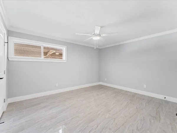 an empty room with wooden floor ceiling fan and window