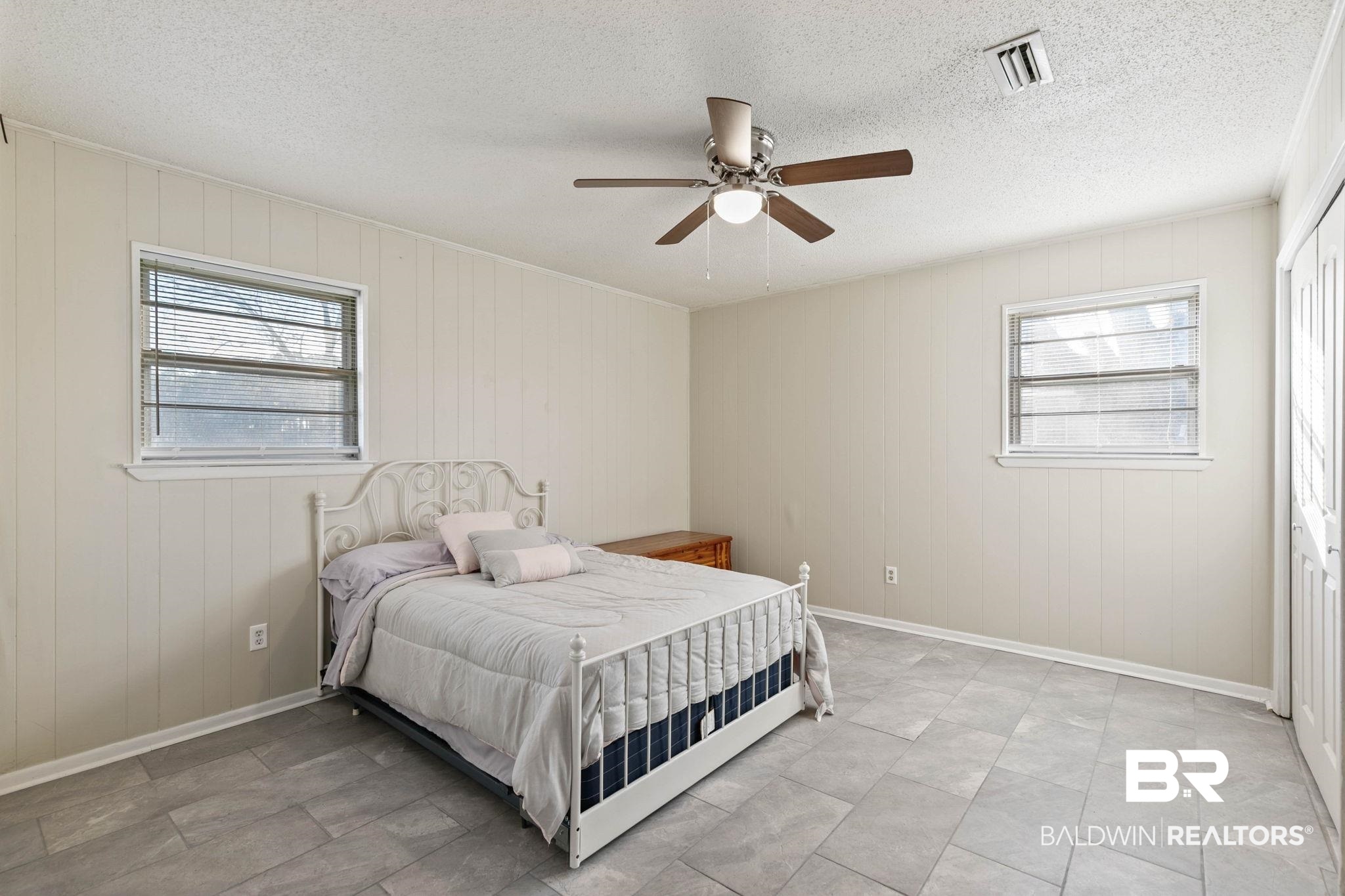 21267 Loop Road Andalusia, AL 36421 - Photo 43 of 72 Bedroom featuring multiple windows, wood walls, a ceiling fan, a textured ceiling, and a closet
