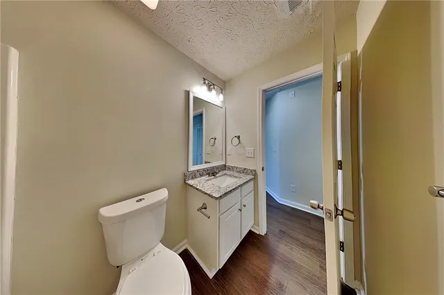 a bathroom with a granite countertop toilet sink and mirror