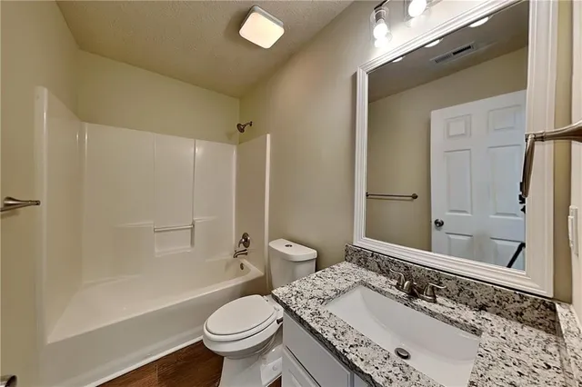 a bathroom with a granite countertop sink a toilet and shower