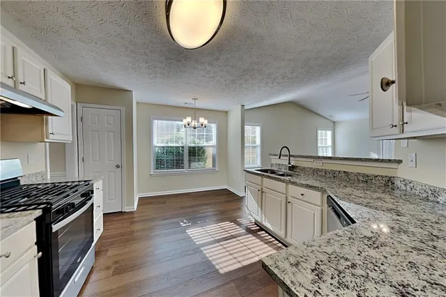 a kitchen with stainless steel appliances granite countertop a stove a sink and a microwave