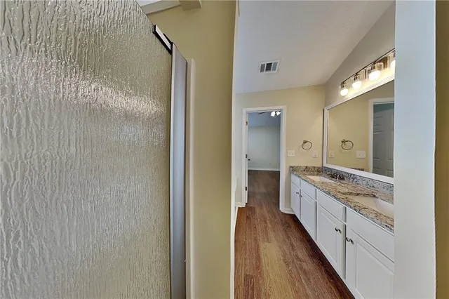 a bathroom with a granite countertop sink a mirror and a shower