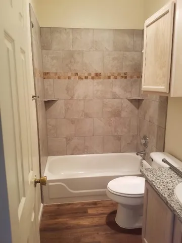 a bathroom with a granite countertop bathtub shower sink vanity and toilet