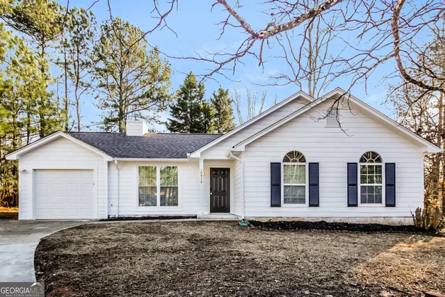 a view of a white house with a yard and large tree
