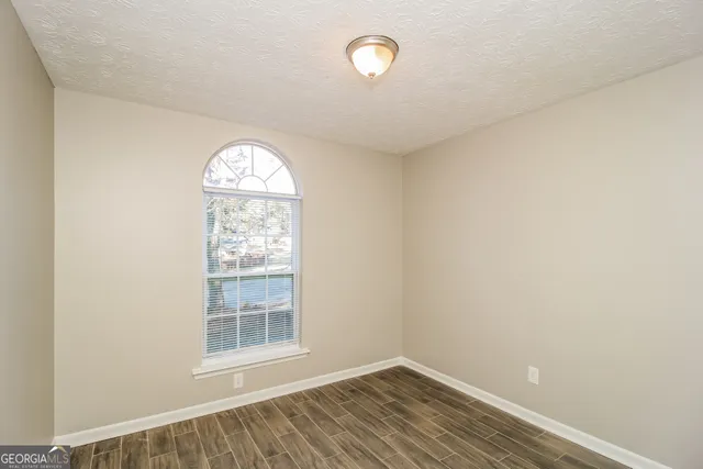 an empty room with wooden floor fan and windows