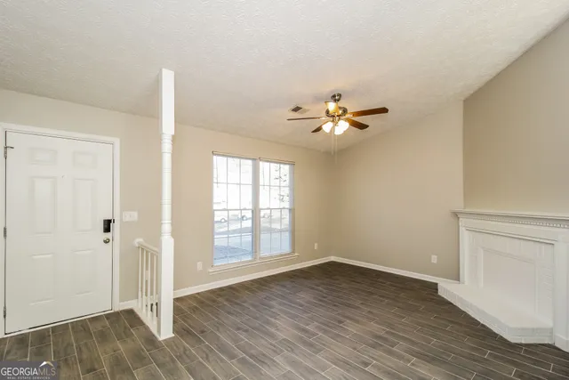 an empty room with wooden floor chandelier fan and windows