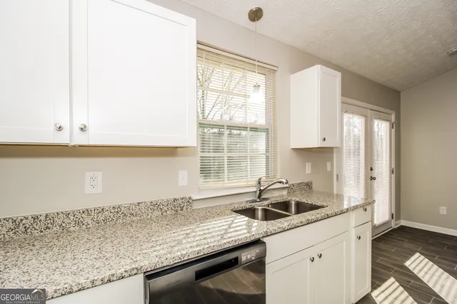 a kitchen with granite countertop a sink and a white wooden cabinets