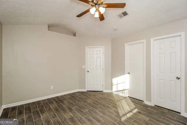 a view of an empty room and chandelier fan