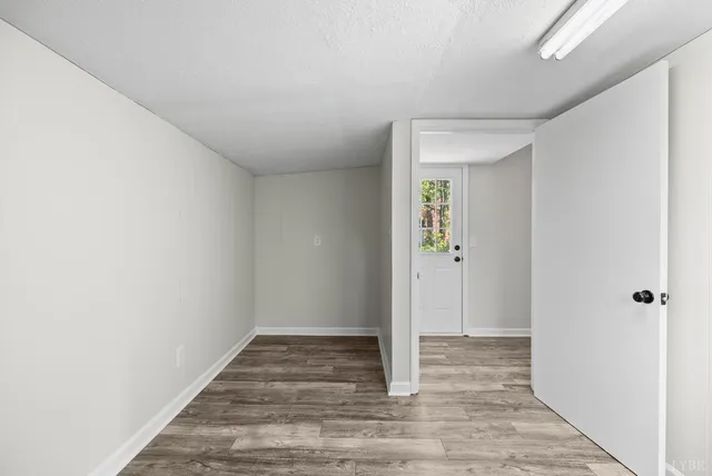 an empty room with wooden floor ceiling fan and window