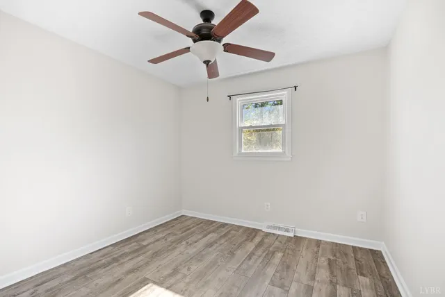 a view of empty room with wooden floor and window