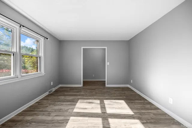 an empty room with wooden floor and a window
